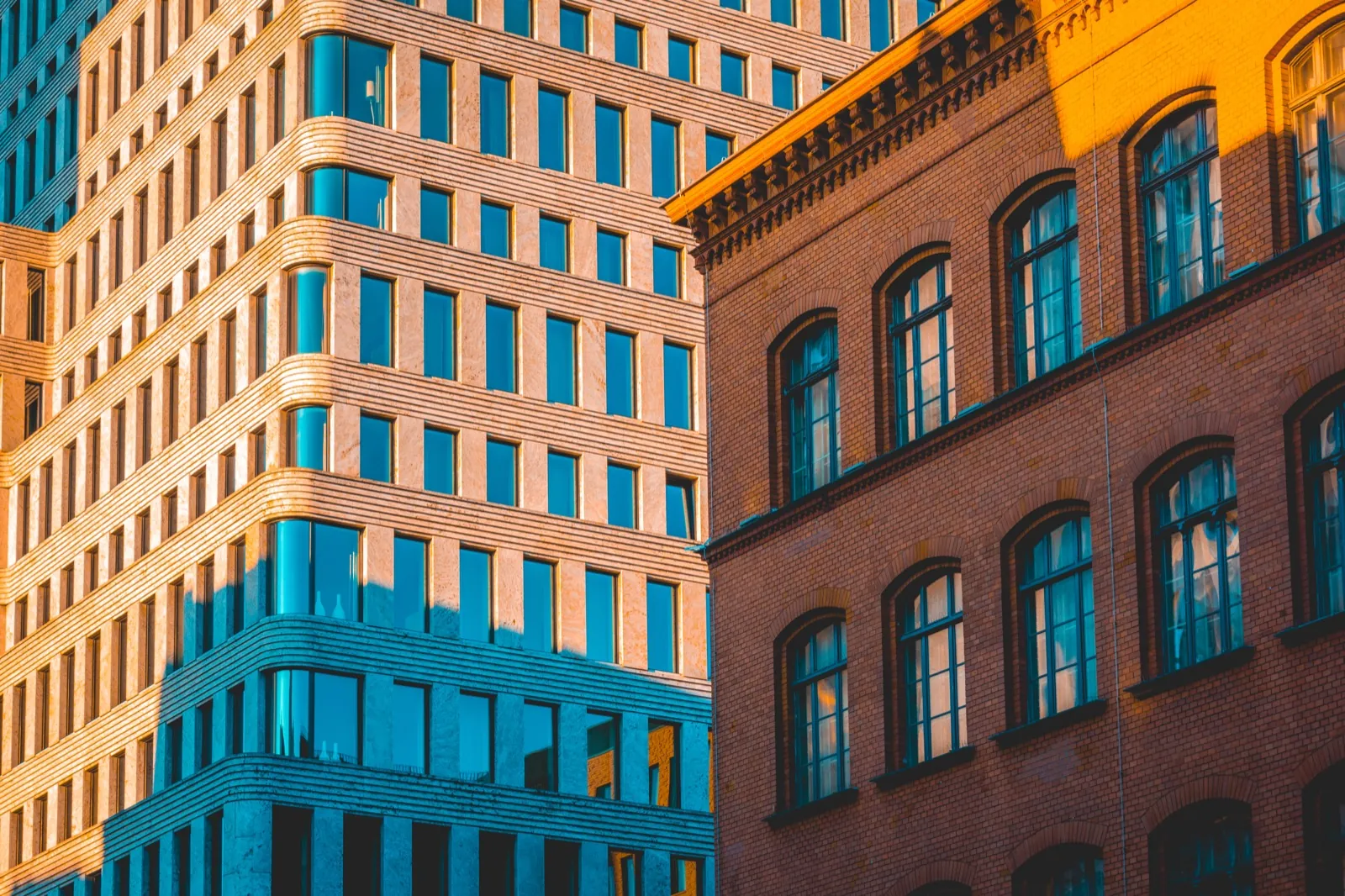 Modern glass office tower beside a brick heritage commercial building